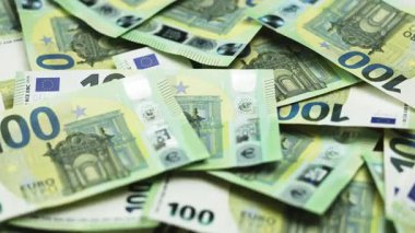 Bir yüzeyde 50 ve 100 banknotluk çeşitli avro banknotları sergilenirken, arka planda ek para birimi kısmen görülebilir