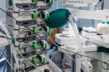 Arkaplanda izleme cihazları ve tıbbi gereçlerle bir hastane odasında düzenlenmiş infüzyon pompaları ve vantilatör dahil tıbbi ekipmanlar