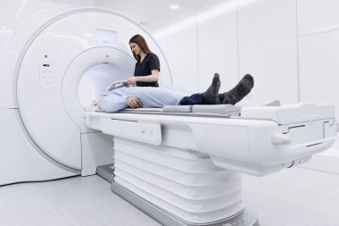 Hasta MRI tarama yatağında teknisyen olarak steril çevresi olan çağdaş bir tıbbi tesiste görüntüleme işlemine hazırlanıyor.