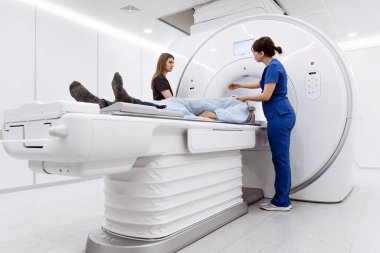 Sağlık uzmanları çağdaş bir tıbbi ortamda görüntüleme işlemine hazırlanırken hasta MRI masasında konumlandırıldı
