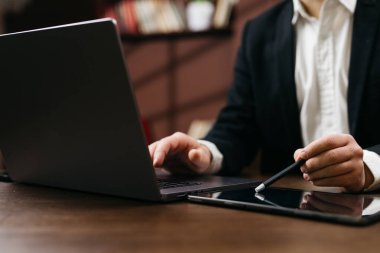 Tablet pc kullanırken dizüstü bilgisayarda çalışan adam