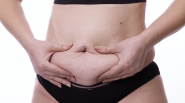 Kadının karnını iki eliyle tutarken, cilt dokusunu ve rengini gösterirken.