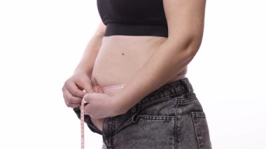 Yetişkin kadın, siyah hasır bluz giyerken ölçü alarak belini ölçüyor.