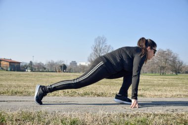 Görme engelli bir kadın parkta egzersiz yapıyor ve esniyor. Yeni zorluklara ulaşmak isteyen körler için güç örneği