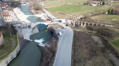 Cuneo vilayeti yakınlarındaki verimli ilkbahar ovalarında süzülen sakin bir nehrin hava aracı görüntüsü. Sıcak güneş ışığı kırsal İtalya kırsalını aydınlatıyor ve yeşil çayırlar akıyor.