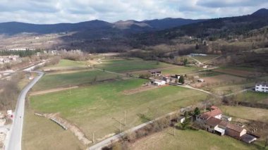 Cuneo vilayeti yakınlarındaki verimli ilkbahar ovalarında süzülen sakin bir nehrin hava aracı görüntüsü. Sıcak güneş ışığı kırsal İtalya kırsalını aydınlatıyor ve yeşil çayırlar akıyor.