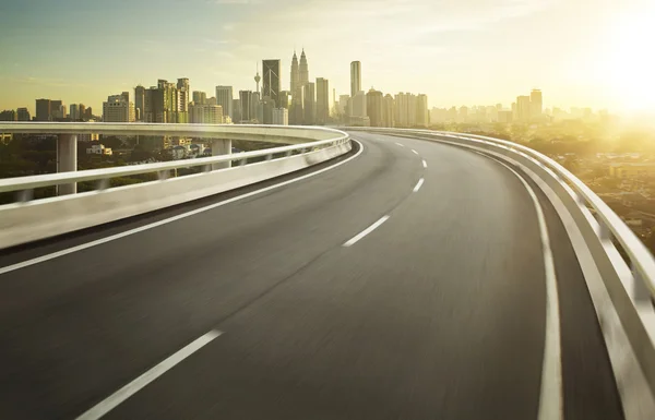 Autobahnüberführung Bewegungsunschärfe mit Stadthintergrund . — Stockfoto