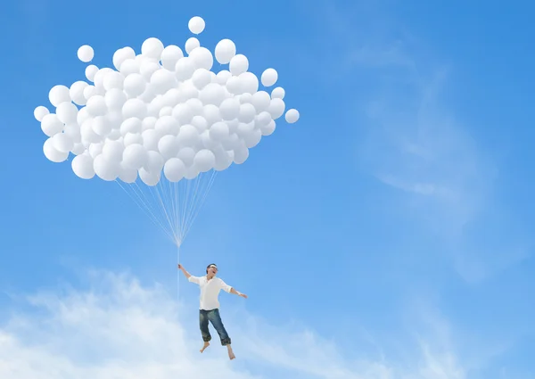 Man flying on bunch of white balloons — Stock Photo, Image