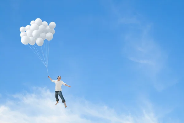 Man flying on bunch of white balloons — Stock Photo, Image