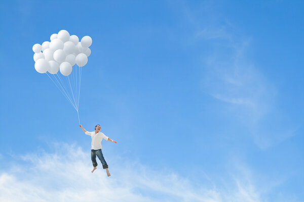 Man flying on bunch of white balloons