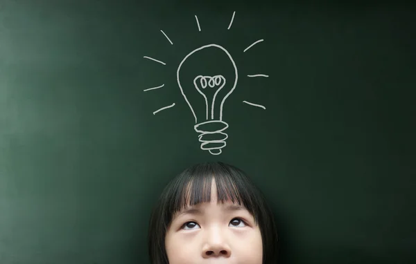 Little girl looking up over blackboard — Stock Photo, Image