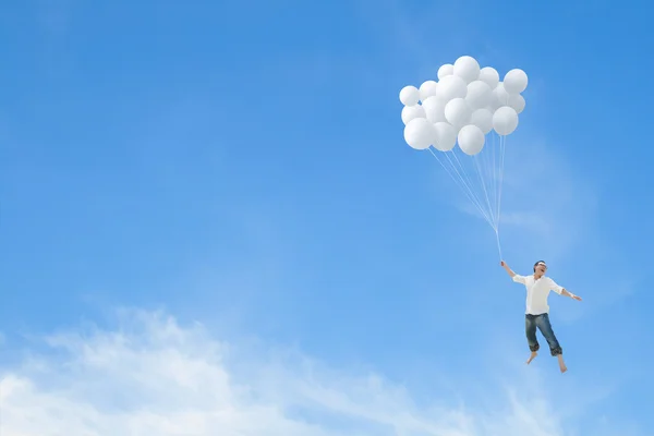 Homme volant sur un tas de ballons blancs — Photo