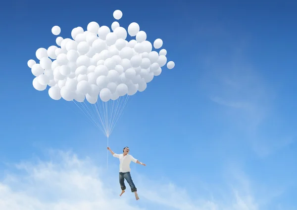 Hombre volando sobre un montón de globos blancos — Foto de Stock