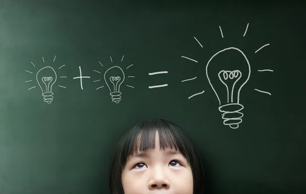 Little girl looking up over blackboard — Stock Photo, Image