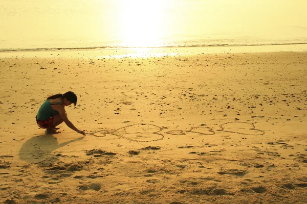 Γυναίκα σχεδίασης καρδιά στην άμμο — Φωτογραφία Αρχείου