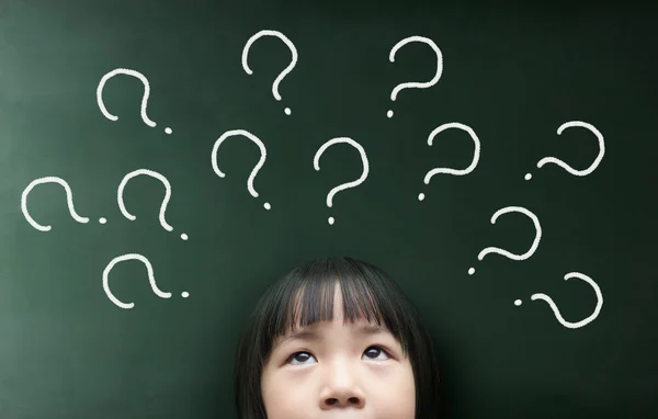 Little girl looking up over blackboard — Stock Photo, Image