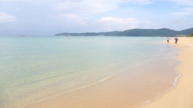 Sandy plaj, deniz, dağlar, bulutlar