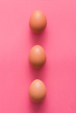 Pembe bir arka plan üzerinde üç yumurta