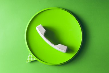 Konuşma balonu simgesinin gündelik nesneler yapılmış yeşil telefon ahizesi