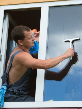 işçi pencereden dışarı yıkamak için eğildi