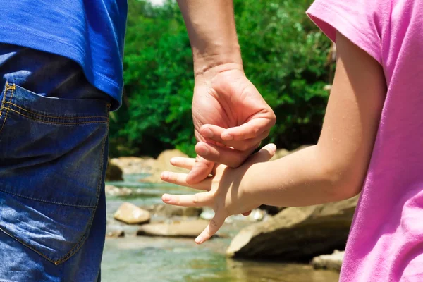 Dad and daughter have joined hands on the river bank