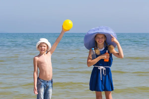 Muchacha y niño muestran que es necesario tomar del sol en el mar — Foto de Stock