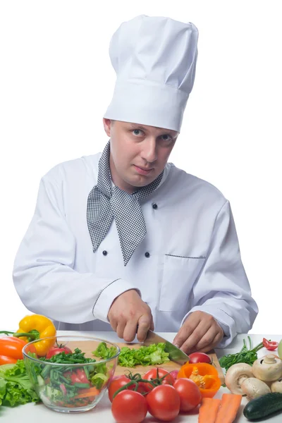 Cook cuts the greens at a table with vegetables — Stock Photo, Image