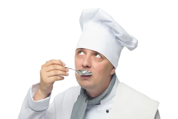Cocinar sosteniendo una cuchara en su mano y tratando de probar — Foto de Stock