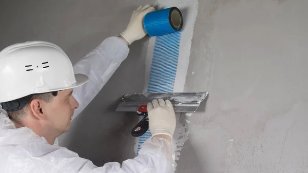 Özel Giysili Bir Işçi Kask Duvarı Mavi Bir Ile Yapıştırıyor — Stok fotoğraf