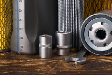 Bir takım araç gereçleri, sarı bir arka plan ve ahşap bir masa, yağ filtresi ve açıcılar, yakın plan.