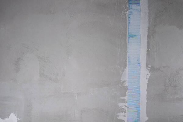 concrete wall, with reinforced tape to strengthen the plastered crack, with space for the inscription