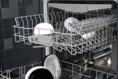 Mutfak arka planında siyah beyaz tabaklar olan bulaşık makinesinin çekmecelerine yakın plan.