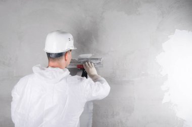 Miğferli ve takım elbiseli bir işçi, karışımı duvarın hizasına, dikiz aynasına yerleştirir.