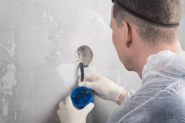 Bir elektrikçi prizlere yeni elektrik kabloları yerleştirir ve tamir eder.