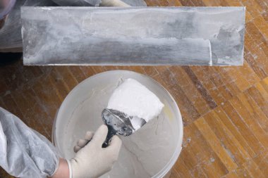 Büyük bir spatulaya yakın çekim, usta bir sıvacı tarafından beton bir duvara macun sürmek için.