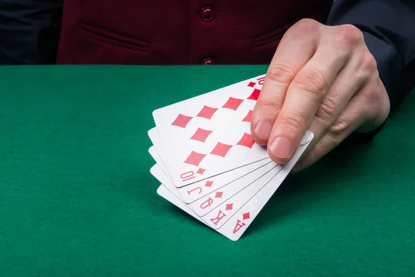 the croupier shows the winning combination in red, in the game of poker, close-up, on the background of a green table