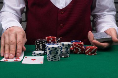 Satıcı poker fişleri yığınının önünde kartlarını açar.