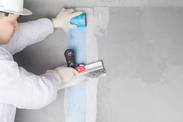 the repairman seals the gap in the wall with mortar and mesh, on the right is a place for the inscription