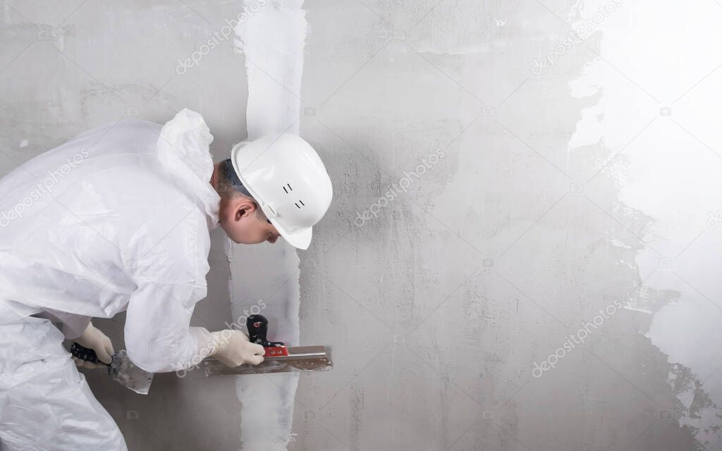 repairman seals a crack in the wall with mortar