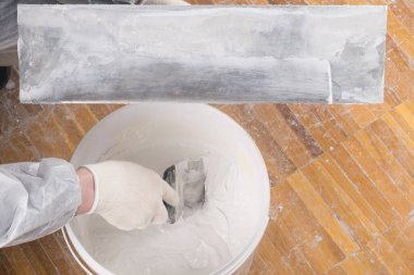 Sıvacı, macun bıçağının üzerine koymak için havan topunu alır ve üzerine yazdığın yere koyar.