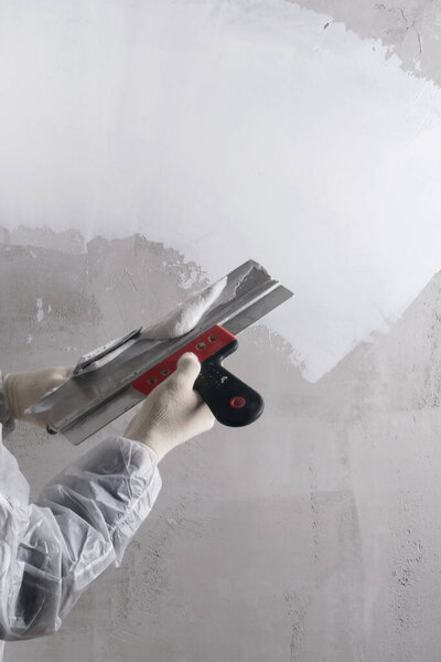 the hands of the plasterer are working on the restoration of the wall