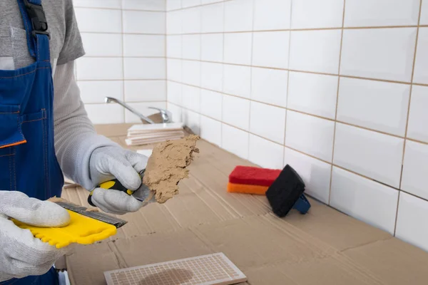 Sullo Sfondo Piastrelle Chiare Maestro Tiene Mano Una Spatola Gialla — Foto Stock