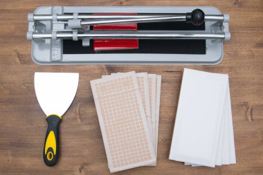 Tahta bir arka planda, bir fayans kesicisi, bir tutkal spatulası, yazıtlar için bir yer var.