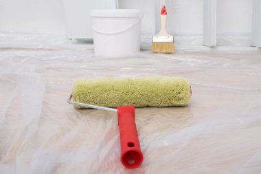 Kapalı mekanda yenileme konsepti: duvar boyası silindiri yerde polietilen ile kaplanmış, işi bitirme hazırlığı