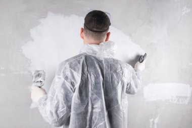 Beton duvar döşeyen bir işçi mala ve havan topuyla, dikiz manzaralı