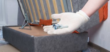 Kanepe montajlı beyaz eldiven ve tamir için cıvatalar.