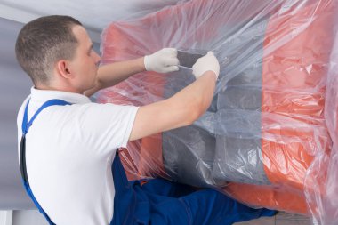 İşçi, yeni kanepeyi teslimat adresine teslim etti. Paketi müşteriye teslim etmeden önce boşalttı.