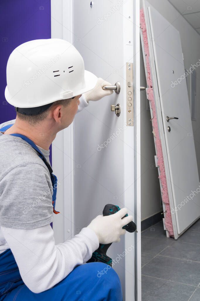 close-up of a worker in uniform, checking the correct operation of the lock of the door mechanism, after replacing and repairing with a screwdriver