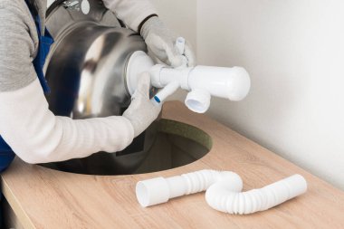 Bir zanaatkar mutfak mobilyaları için lavabonun üzerine sifon monte eder.