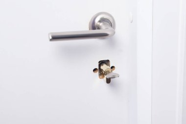 Kırık beyaz ön kapı kilidi ve kolu, yakın plan.